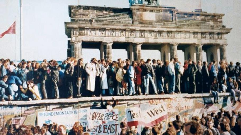 Menschen stehen auf der Berliner Mauer vor dem Brandenburger Tor