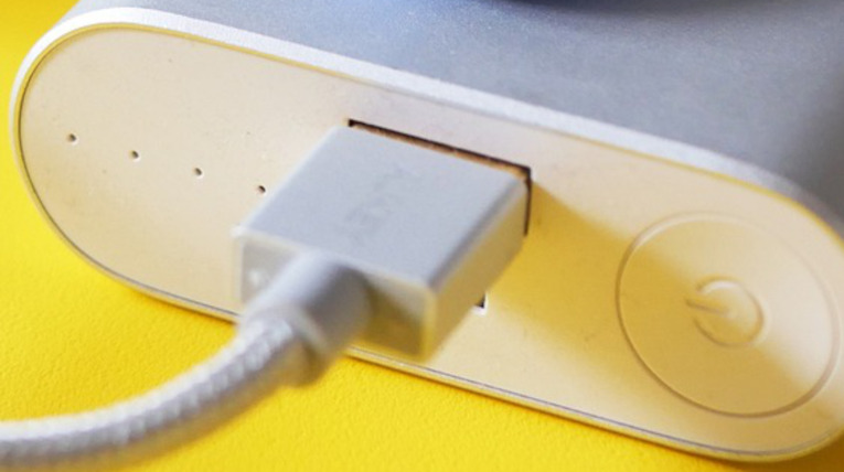 Nahansicht Powerbank weiß, USB-Kabel steckt in Anschluss, Standby-Knopf
