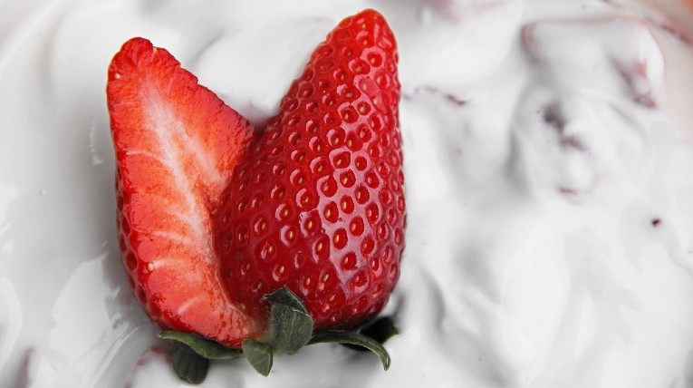 Aufgeschnittene Erdbeere liegt auf weißem Joghurt