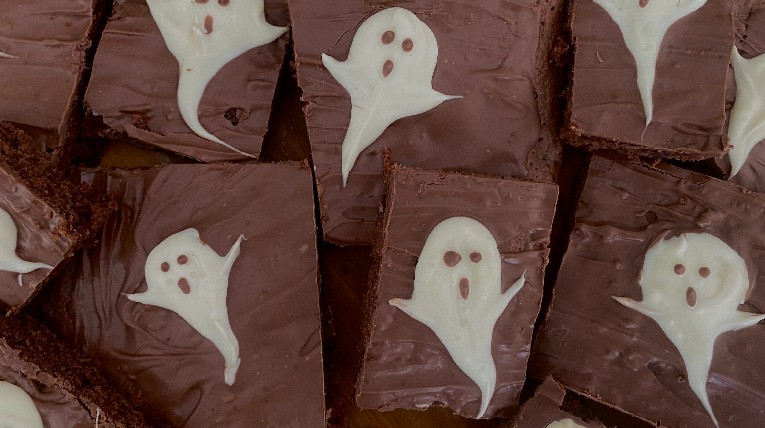 Zu sehen sind Brownies, auf denen mit weißer Schokolade Geister gemalt sind. 