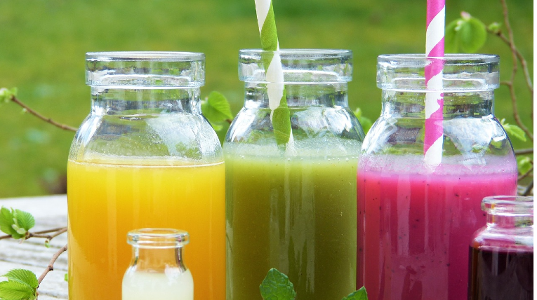 Zu sehen sind drei Gläser, die mit Smoothies gefüllt sind. Die Smoothies sind gelb, grün und lila. 