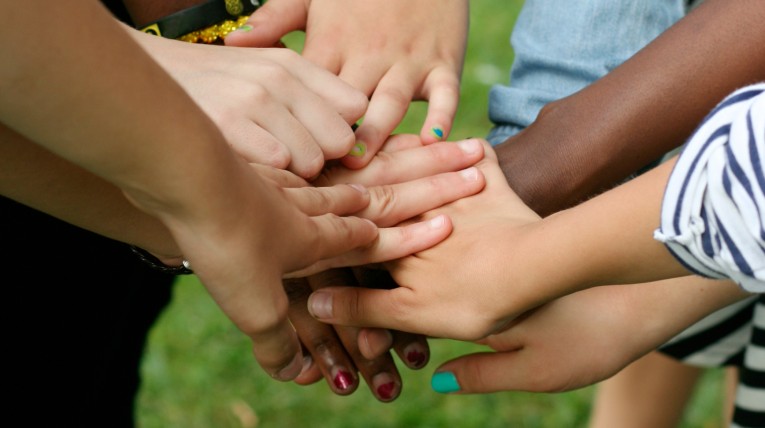diverse Kinderhände, die aufeinander gelegt sind 