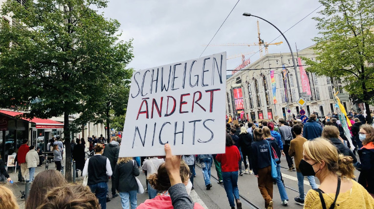 selbstgebasteltes Demoplakat mit der Aufschrift Schweigen ändert nichts