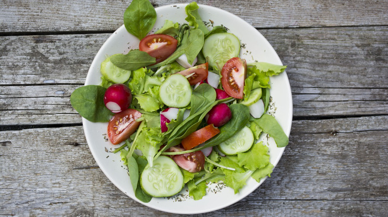 Salat auf einem Teller mit Gurken, Tomaten, Radieschen und verschiedenen Salat-Sorten
