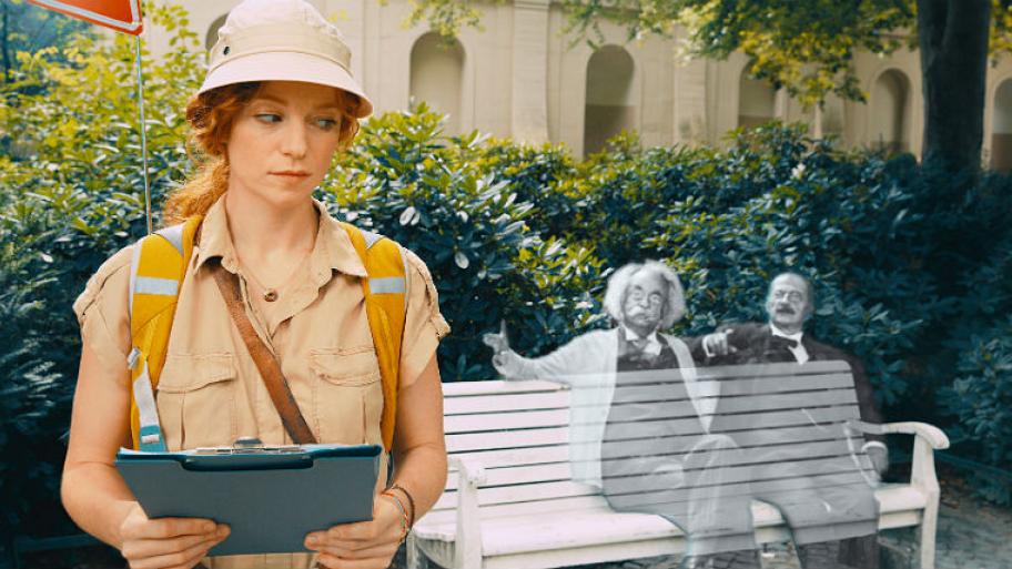 Die hauptfigur Cleo, schaut auf eine Bank auf der die Geister von Albert Einstein und Heinrich Schliemann sitzen. 