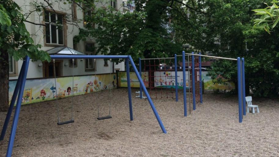 Außenbereich mit Schaukeln und Budeelkiste umgeben von Bäumen