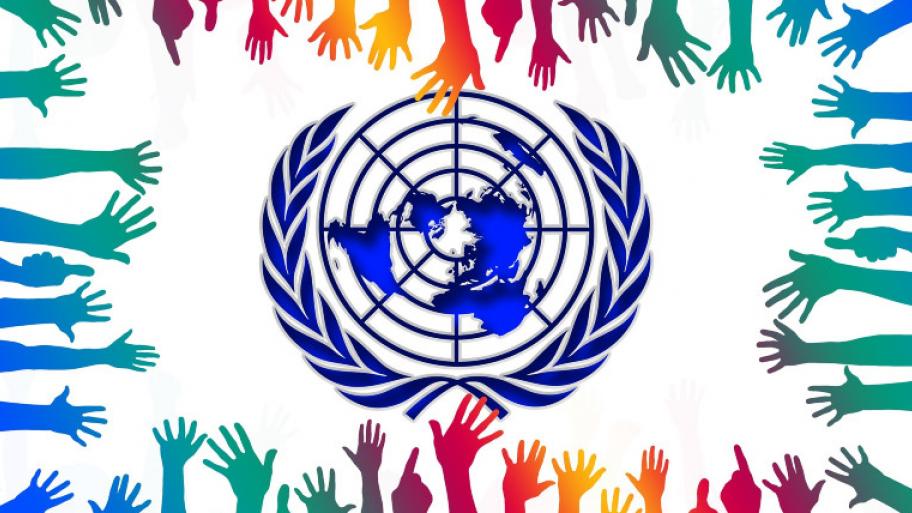 in der Mitte das Logo der Vereinten Nationen, im Kreis darum greifen bunte Hände danach