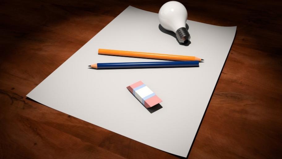 auf einem Tisch liegen ein leeres Blatt Papier, ein Bleistift, ein Radiergummi und eine Glühbirne