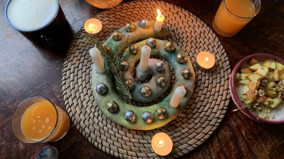 Adventsspirale mit Schokokugel und Kerzen; eine Kerze brennt; Orangensaft, heiße Schokolade und Porridge stehen drumherum 