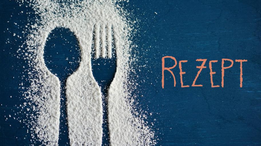 Löffel- und Gabelabdruck in Puderzucker auf einem blauen Tisch, Textfeld: "Rezept" 