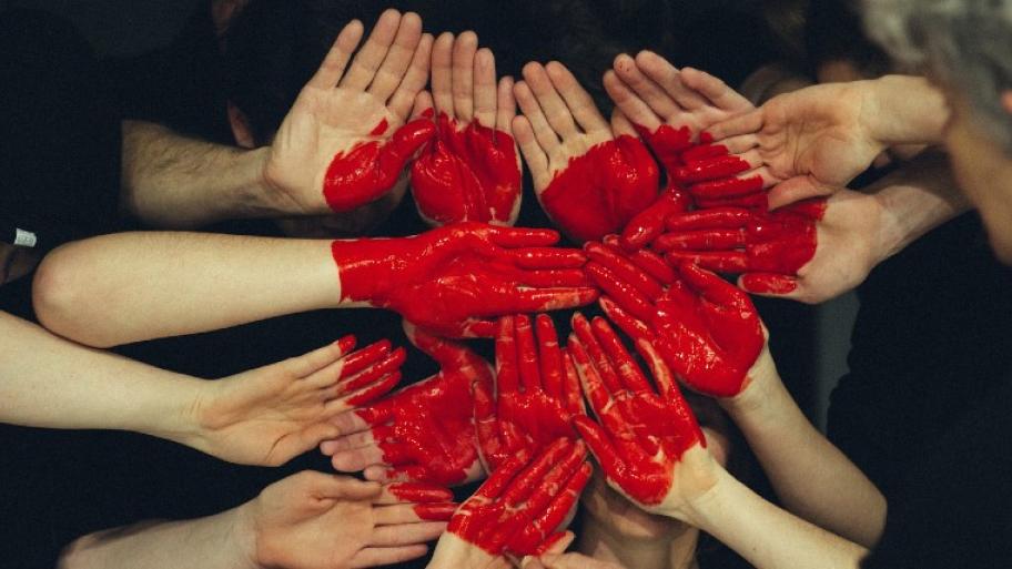 Hände teilweise mit roter Farbe angemalt, zusammen ergeben sie ein Herz