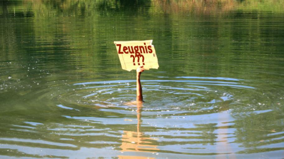Hand ragt aus Wasser mit Schild auf dem Zeugnis steht