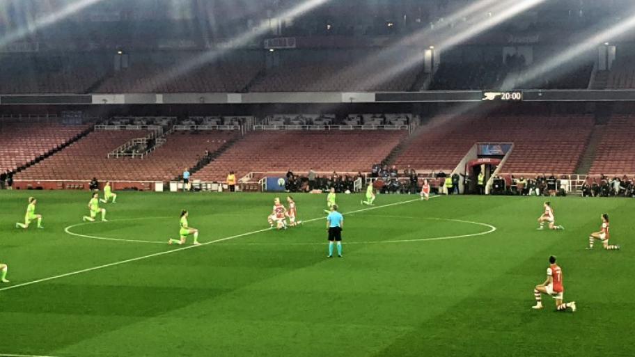 die Fußballerinnen der Teams Arsenal WFC und VfL Wolfsburg knien vor Spielbeginn jeweils in ihrer Hälfte auf dem Spielfeld