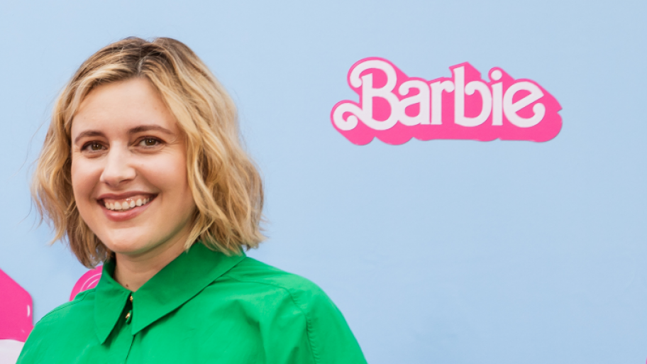 Regisseurin Greta Gerwig steht vor Stellwand mit "Barbie" Logo