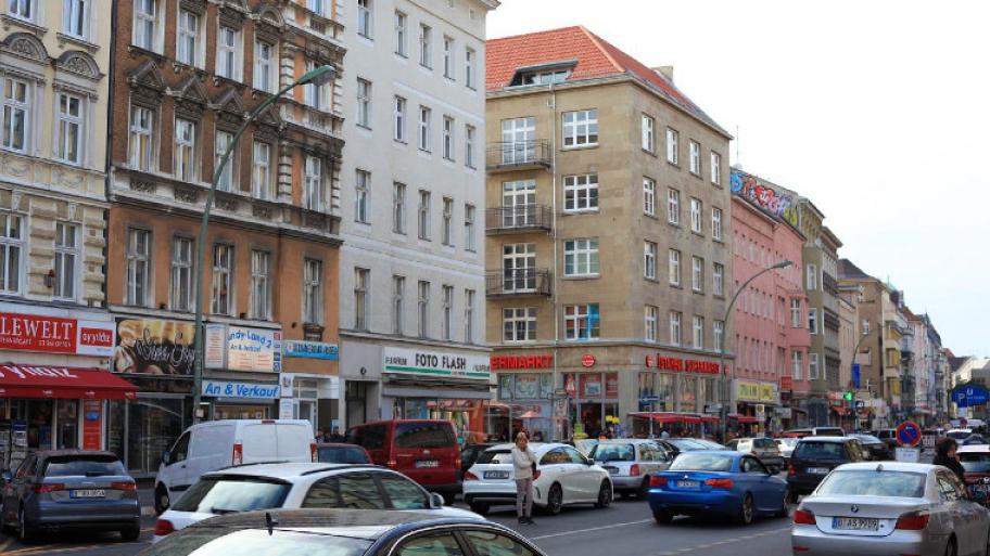Berliner Innenstadt: Straßenrand mit Gebäuden und kleinen Läden, auf der Straße Autos