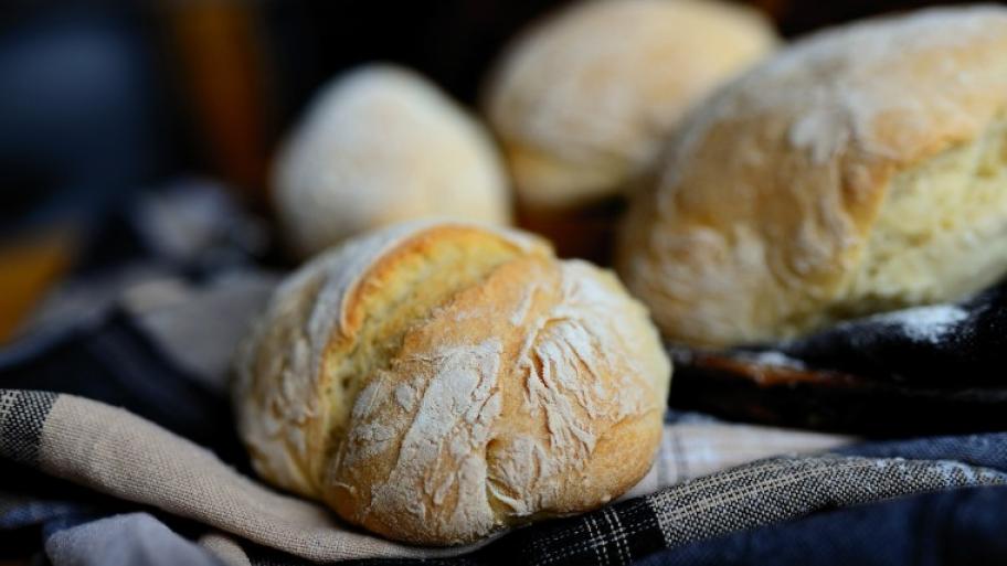 auf einem blau-weiß karierten Geschirrtuch liegen mehrere helle Brötchen