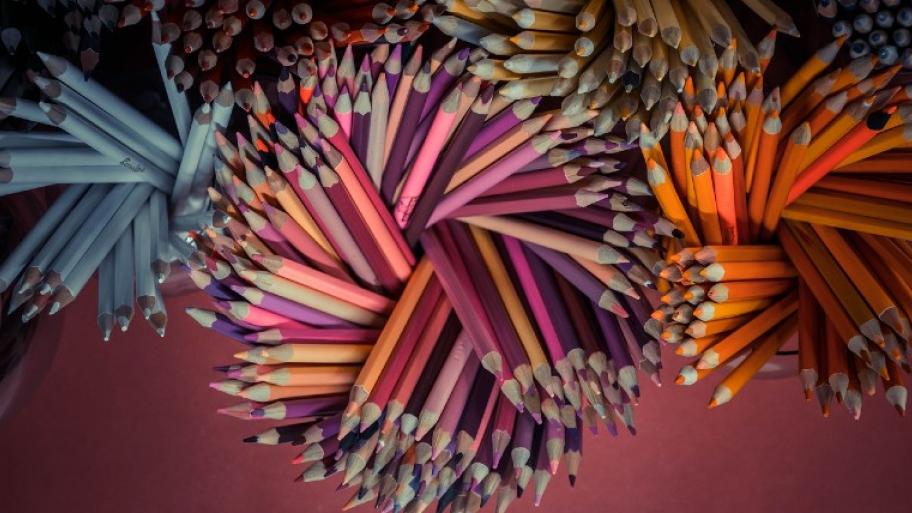 Buntstifte stehen in nach Farben sortiert in Behältnissen, aufgefächert wie eine Blume/Wirbel