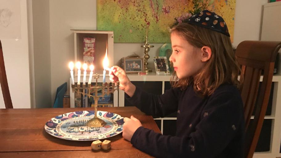 Ein Kind zündet Kerzen der Chanukkia an