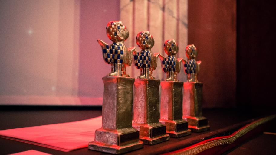 Deutscher Kinder- und Jugendpreis: auf rotem Samt stehen nebeneinander vier goldenen Figuren, Preise für die Gewinnerinnen und Gewinner