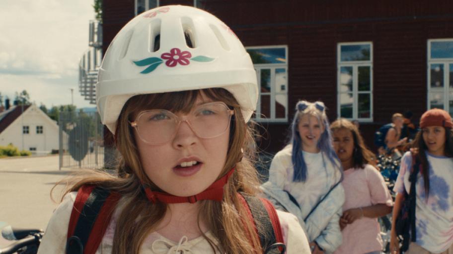 ein braunhaariges weißes Mädchen mit einer 80er Jahre großen Brille und einem Fahrradhelm schaut mit offenem Mund nach rechts