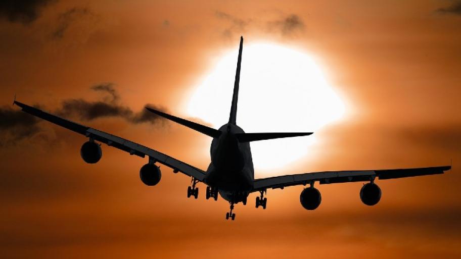 ein Flugzeug fliegt in den Sonnenuntergang, der Himmel ist dunkelorange