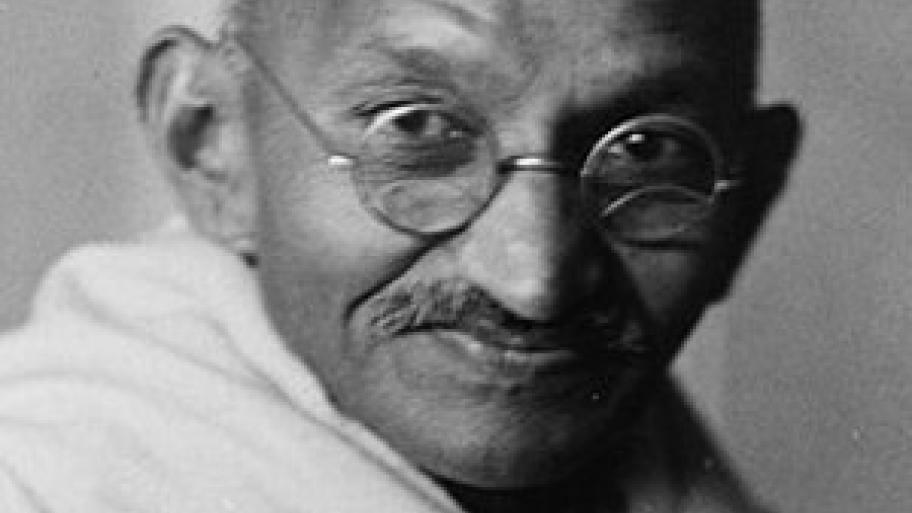 Eine schwarz-weiß-Fotografie von Mahatma Gandhi, ein alter Mann mit Brill und einem Tuch um den Schultern