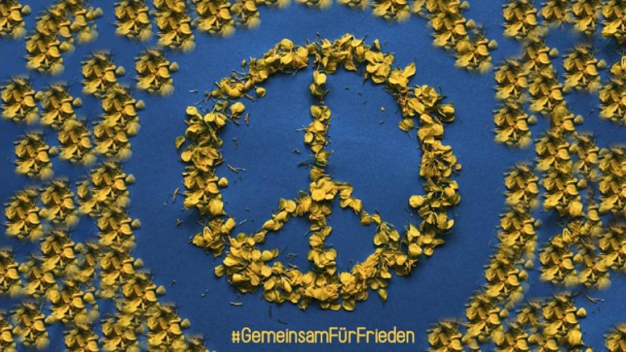 Peace-Zeichen aus gelben Blütenblättern gelegt; unten steht: #GemeinsamFürFrieden