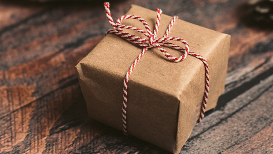 Geschenk eingepackt in braunem Geschenkpapier und rot-weiß gestreifter Schnur