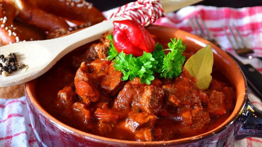 Eine Schüssel gefüllt mit Gulasch. Also Fleisch in viereckigen Stücken, in rot brauner Soße. 