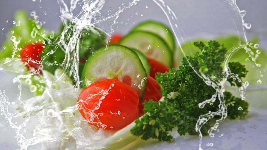 Gurke und Tomate und Petersilie; ums Gemüse wirbelt ein Wasserstrahl