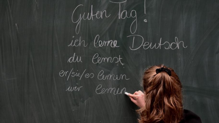 Ein Jugendlicher schreibt: Ich elerne Deutsch an eine Tafel