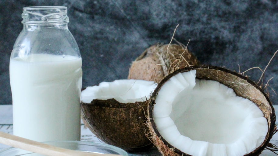 Aufgeschnittene Kokosnuss und Milch in Milchflasche