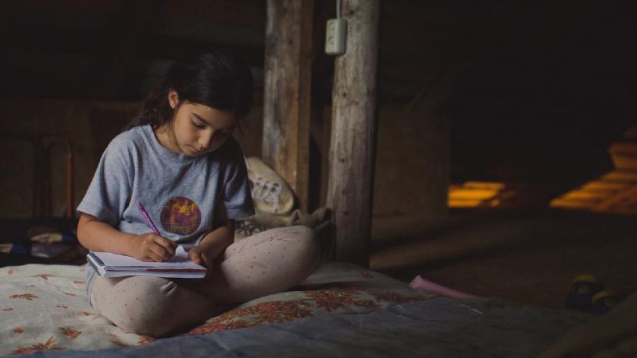 Ein Mädchen lernt auf dem Bett in einer Holzhütte