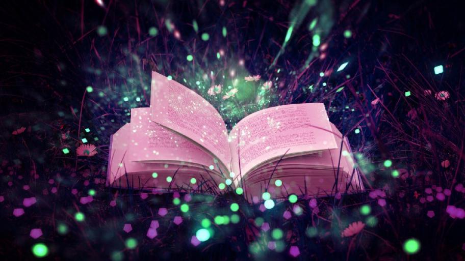 Buch liegt aufgeklappt im Gras und leuchtet rosa, aus dem Buch spühen bunte Funken