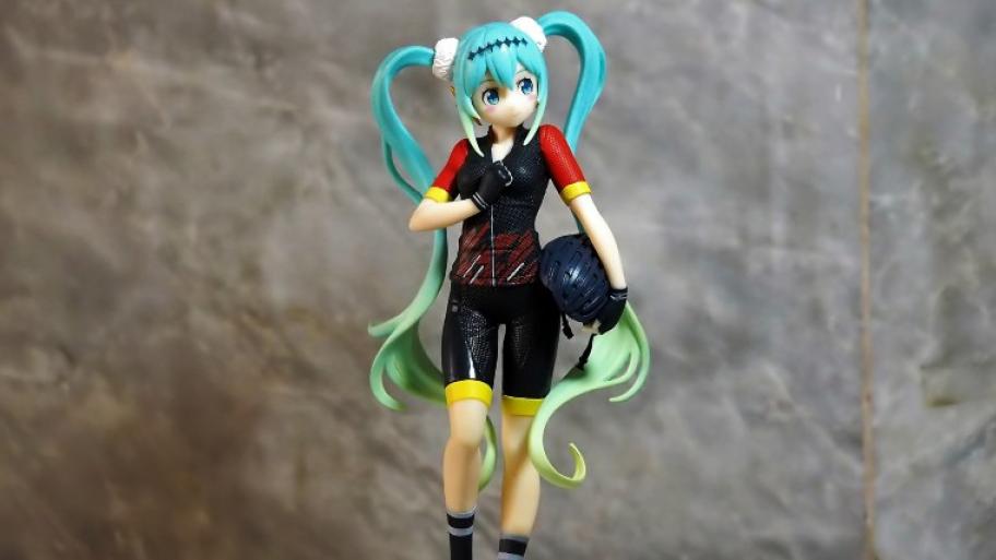 Figur: Hatsune Miku, mit blauen langen Haaren, die zu zwei Zöpfen zusammengebunden sind; sie trägt Sportkleidung