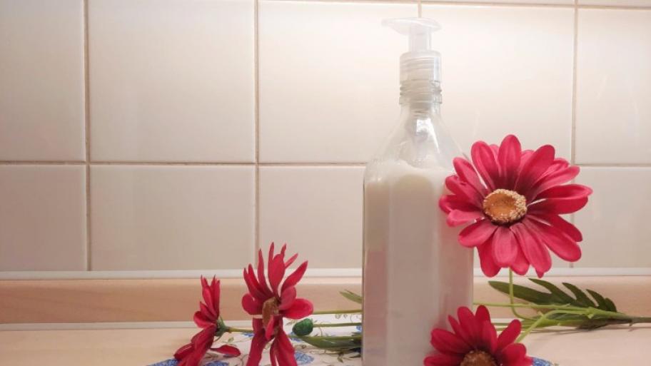 Duschgel in Glasflasche mit pinken Blumen dekoriert