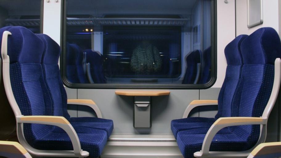 der Innenraum der deutschen Bahn ist zu sehen. Im Bild kann man vier dunkelblaue Sitze einer Regionalbahn erkennen, die gegenüber voneinander sind. In der Mitte ist ein kleiner Tisch an der Wand befestigt