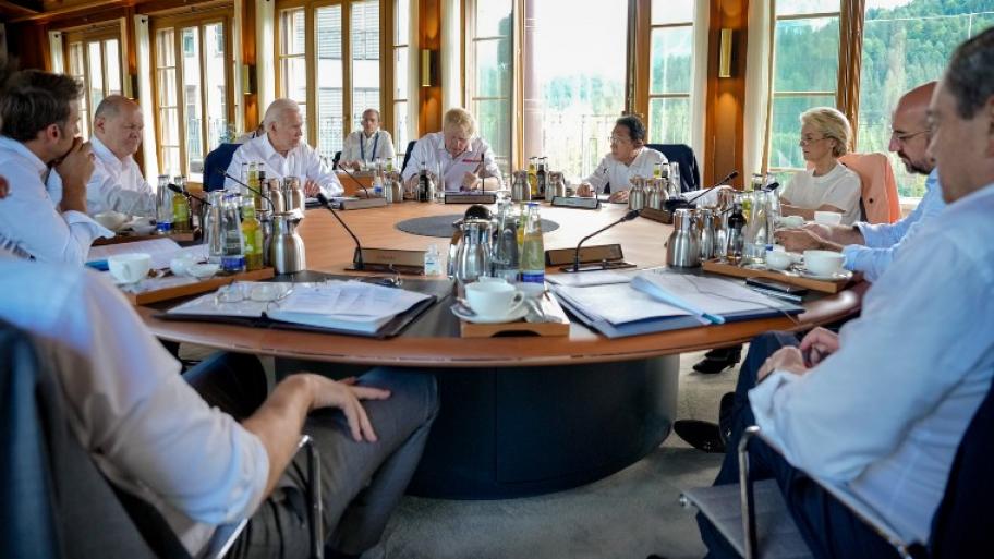 an einem großen, runden, hölzernen Tisch sitzen die Teilnehmenden Staats- und Regierungschef*innen des G7-Gipfels 2022 auf Schloss Elmau in Bayern, Deutschland