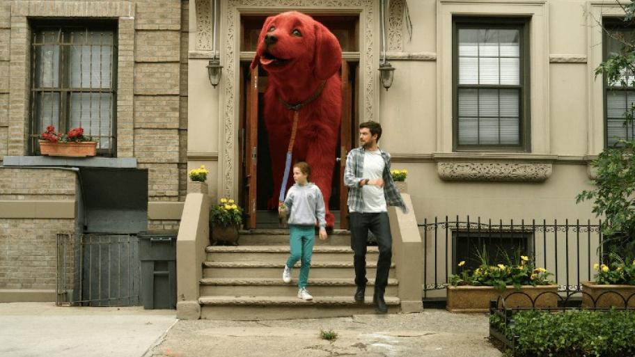Clifford der große rote HUnd wird von Emely, dem Kleinen Mädchen in grauem Hoodie an der Leine durch die Haustür geführt. Links daneben läuft ein jungaussehender Mann mit dunkelbraunen Haaren