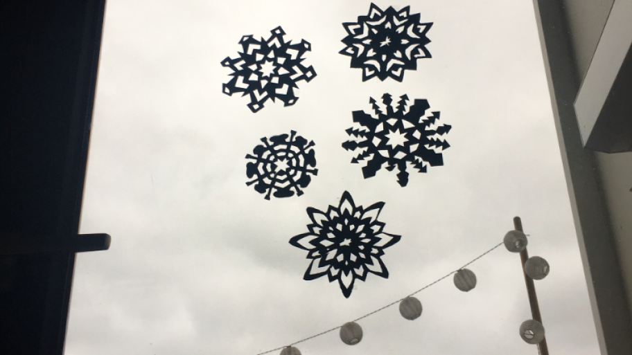Schneeflocken aus Papier ausgeschnitten kleben am Fenster
