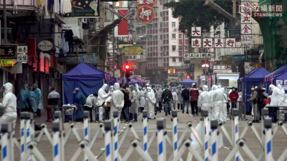 Straße in Shanghai mit Menschen in weißen Schutzanzügen.