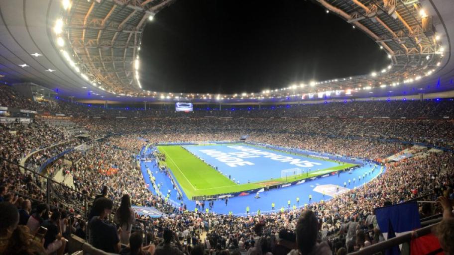 das Pariser Nationalstadion "Stade de France" hell erleuchtet, die Ränge voll besetzt, der Rasen noch leer, oben Blick in den Abendhimmel