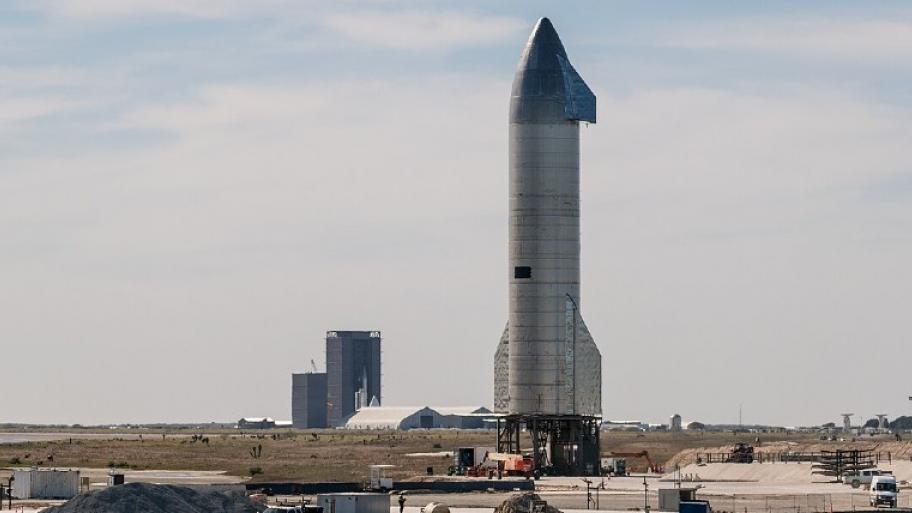 Eine Rakete steht auf dem Boden und ragt in die Höhe. Im Hintergrund sieht man nur Himmel.
