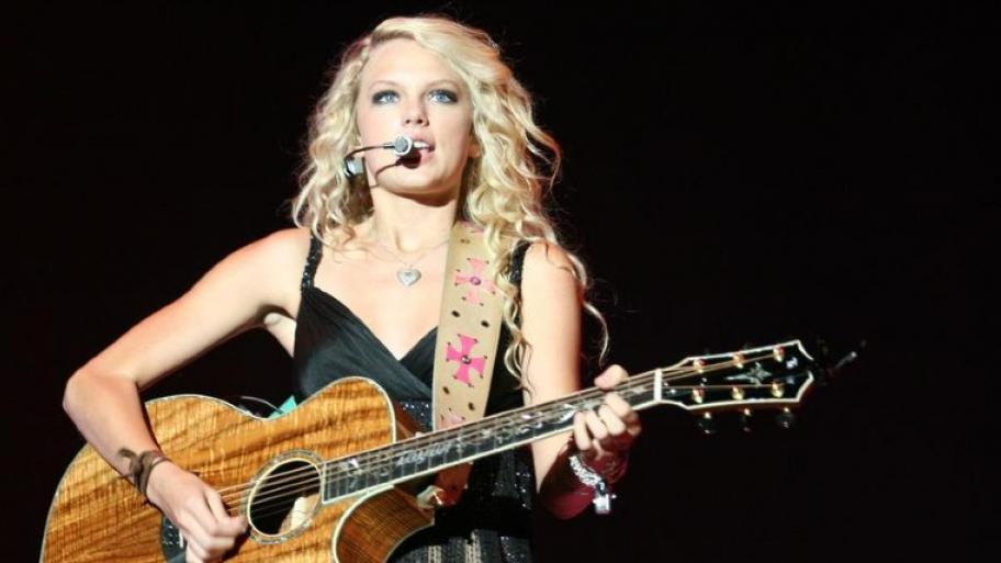 die Sängerin Taylor Swift auf der Bühne performed einen Song mit Gitarre auf der Bühne
