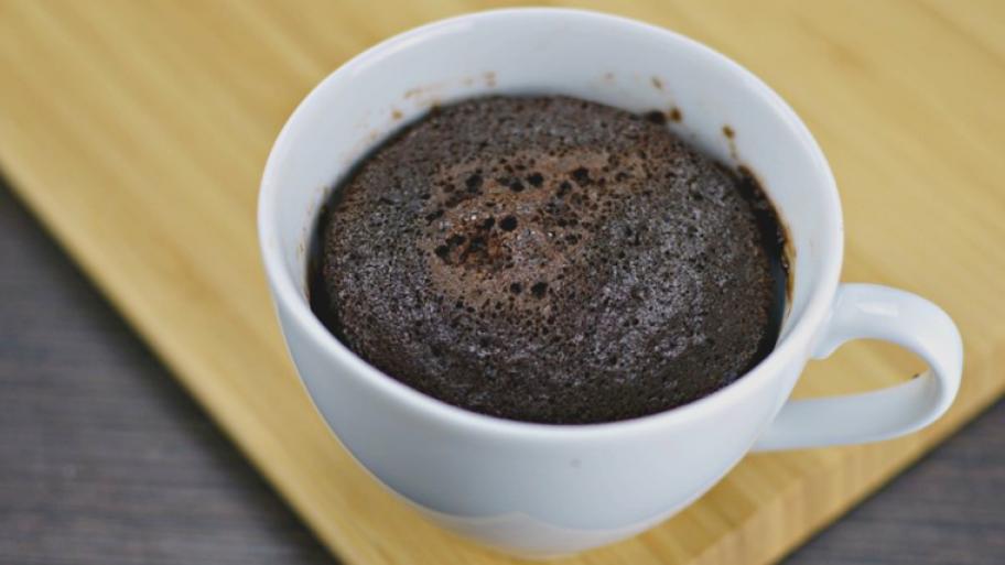 Brownie in Tasse gebacken; weiße Tasse steht auf Holzbrett
