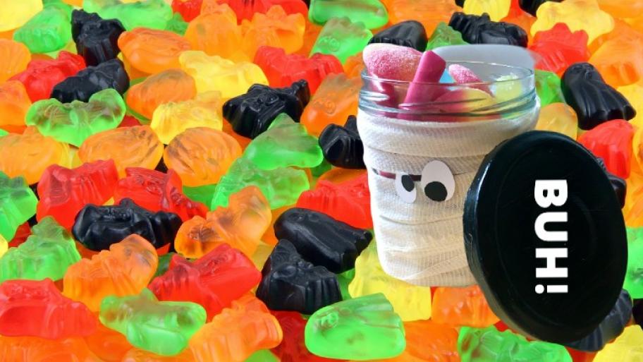Gläser-Geist gefüllt mit Süßigkeiten steht auf bunten Halloween-Gummibärchen