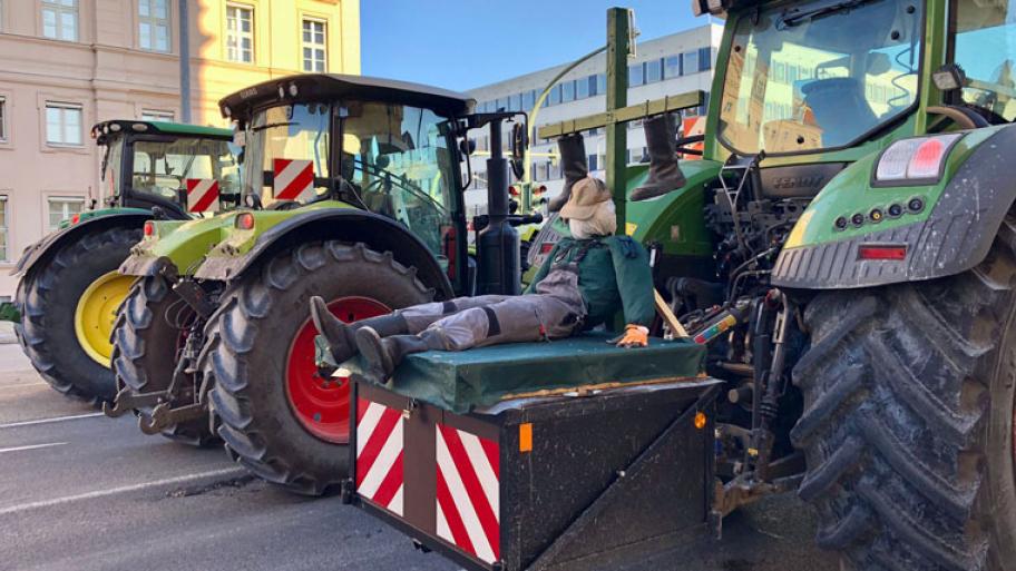 Großaufnahme von drei Traktoren auf der Straße, auf einem sitzt eine lebensgroße Stohpuppe