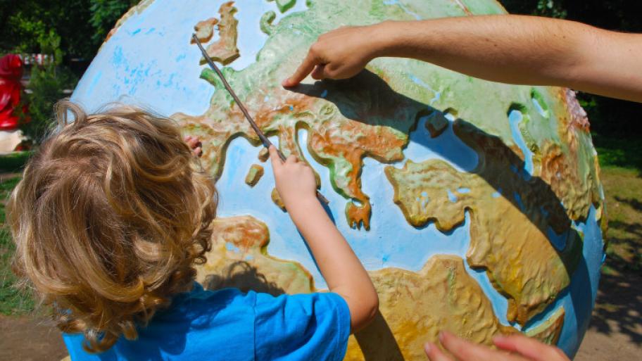 Kind wird auf einem großen Globus gezeigt, wo Europa liegt