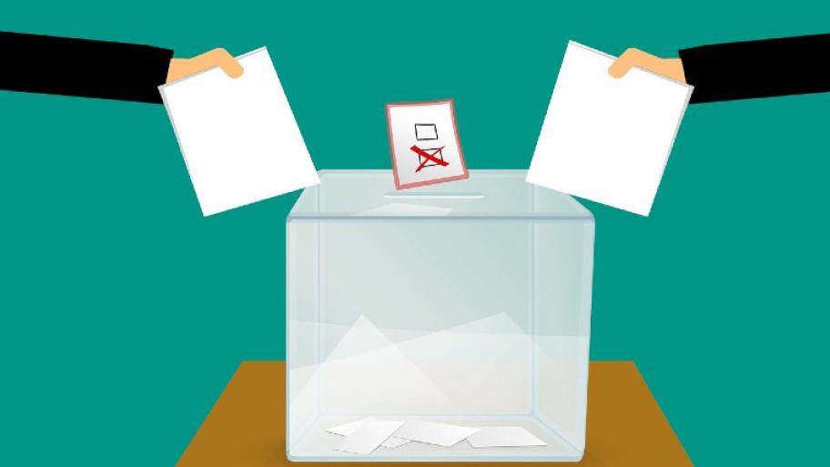 Mohamed_hassanine Illustration einer Wahlurne, mit Stimmzellt und zwei Händen, die mit einem Zettel zur Urne zeigen