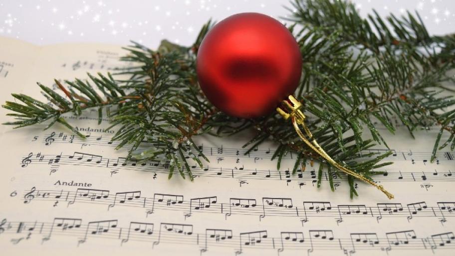 Musiknoten und darauf liegt ein Tannenzweig und eine rote Weihnachtsbaum-Kugel
